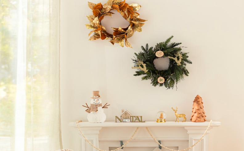 guirlandas de Natal pendurados na parede da sala acima da lareira, além de enfeites como boneco de neve, árvore de Natal pequena e outros adornos.