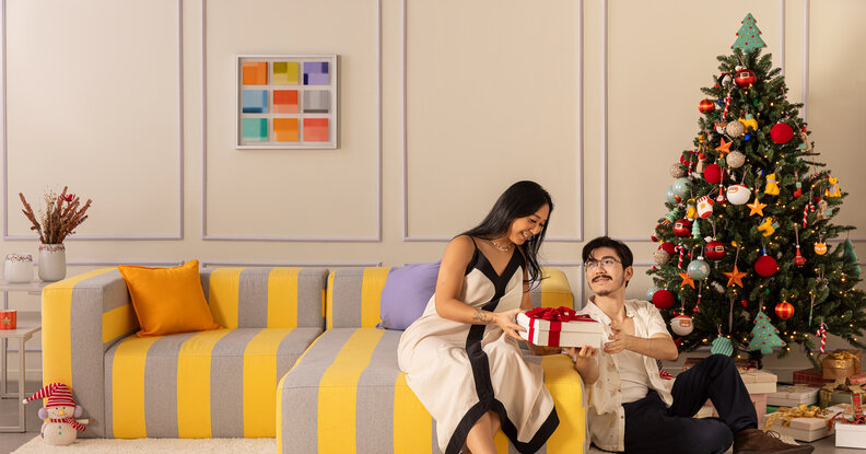 ideias de brincadeira para o natal com duas pessoas na sala de estar trocando presentes para amigo secreto para deixar essa data mais divertida.