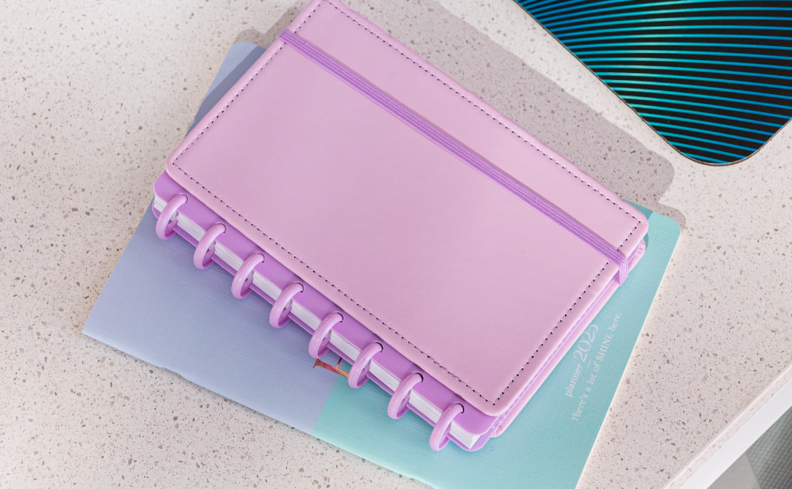 saiba o que é planner, como usar e quais são os principais modelos, com um modelo em lilás, com espiral para facilitar a organização.