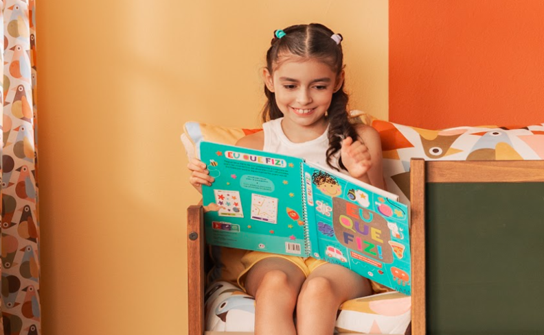 livros para crianças de 2 anos com uma menina sentada em um escorregador cama lendo o livro preferido dela.