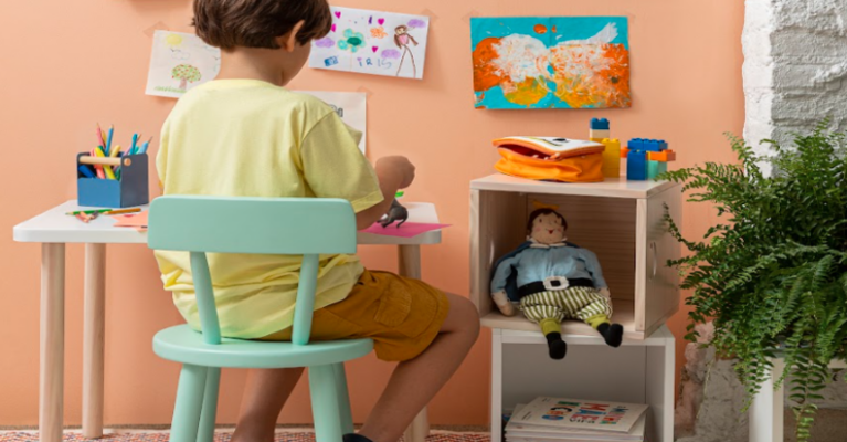 livros para crianças de 3 anos. com um menino sentado no cantinho da leitura escolhendo o livro que deseja ler.