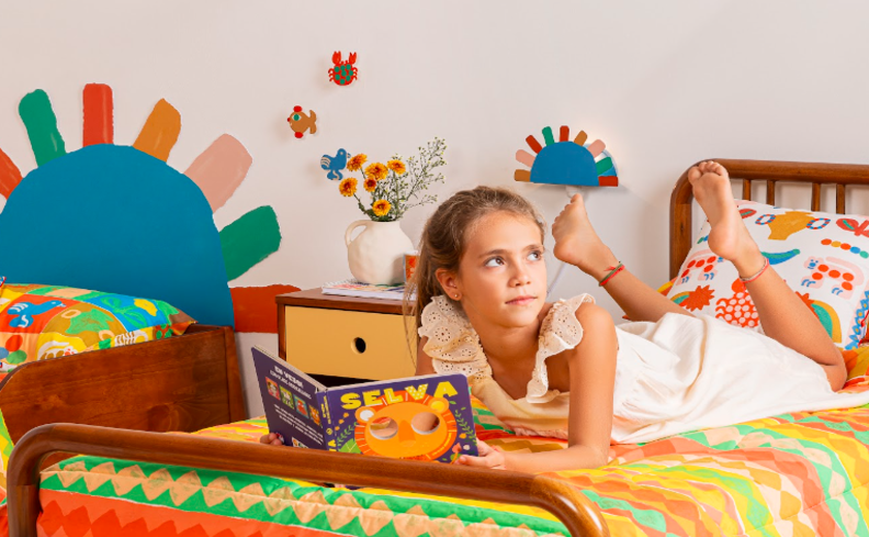 livros para crianças, com uma menina deitada de bruços na cama, pensando nas próximas histórias que ela deseja ler.