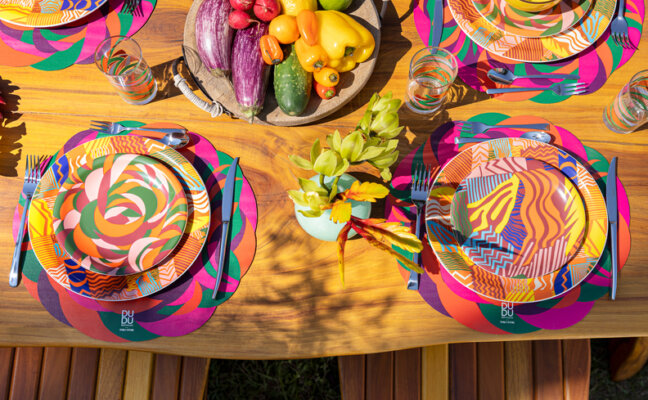 decoração de carnaval em casa com mesa posta Carnaval com diversas cores vibrantes nos pratos, jogo americano e copos.