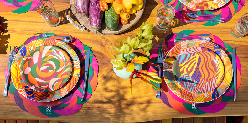 decoração de carnaval em casa com mesa posta Carnaval com diversas cores vibrantes nos pratos, jogo americano e copos.