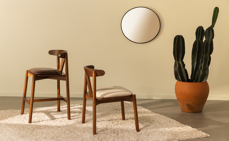 espelho grande para sala de jantar em um modelo redondo pequeno, além de duas cadeiras, tapete e um vaso com planta.