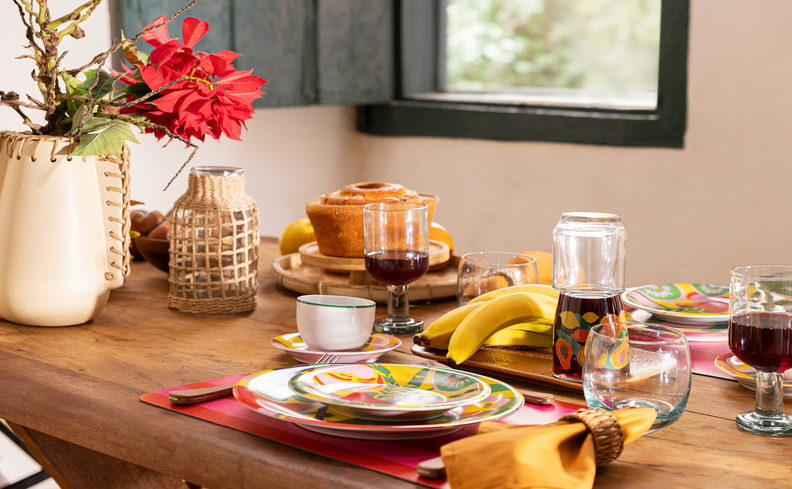 mesa posta carnaval com pratos, jogo americano, copos, vasos para enfeitar a mesa e diversos alimentos para receber os amigos e a família.