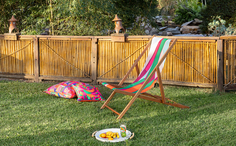 mesa posta simples de carnaval com espreguiçadeira, almofadas. Além de pratos e copos em uma bandeja para fazer uma refeição ao ar livre.