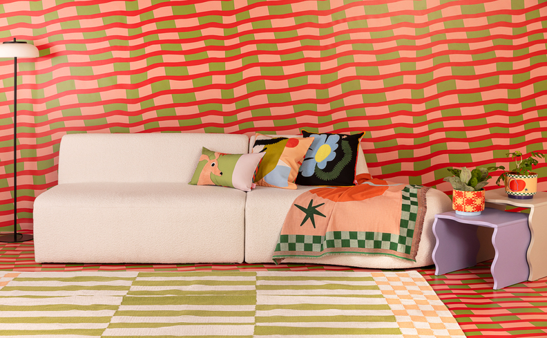 cores fortes e vibrantes para compor a decoração da sala de estar com um sofá branco, parede colorida com vermelho e verde, além de tapete, luminária de chão, manta para sofá, almofadas e mesas de poio.