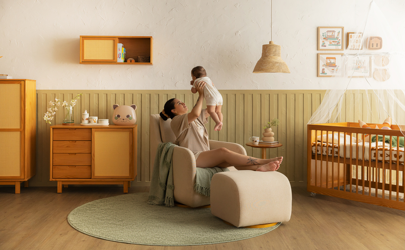 decoração de quarto de bebê safari com cores terrosas, móveis em madeira, uma poltrona de amamentação com uma mãe segurando o bebê, além de diversos itens decorativos com o tema de bichos.