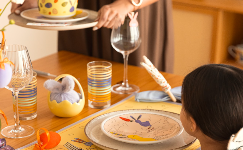 café da manhã Páscoa simples com uma mesa posta com copo, taças, pratos, talheres e itens temáticos dessa data comemorativa.