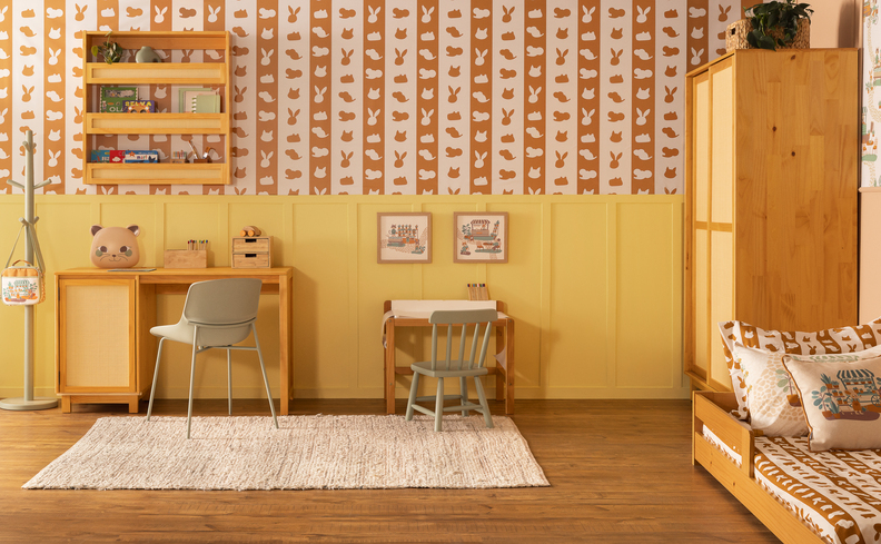 quarto infantil com a decoração de safari com móveis em madeira, tons terrosos, papel de parede de bichos, quadros decorativos, tapete, escrivaninha e cadeira.