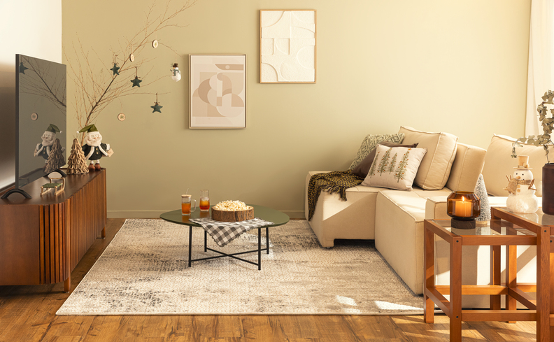 sofá confortável para sala pequena com sofá retrátil, rack, tapete, mesa de centro redonda, mesa lateral, diversas almofadas e quadros decorativos.