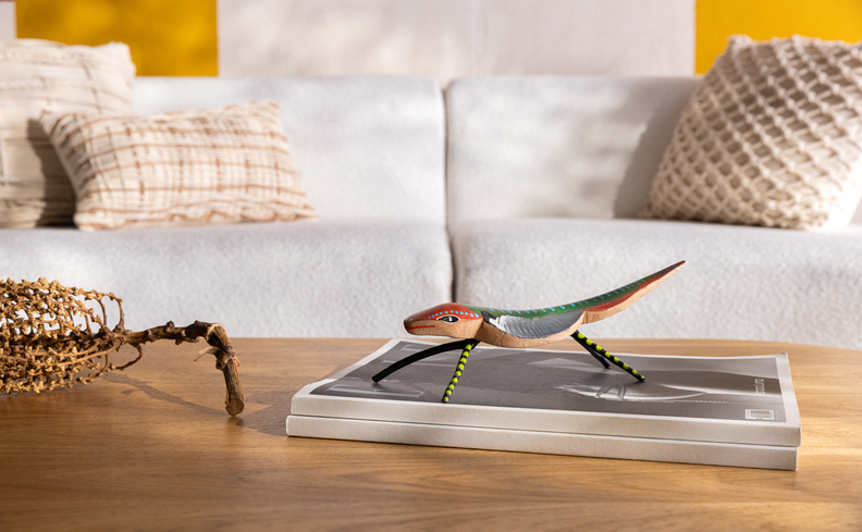 artesanato brasileiro com peças escupidas na madeira para decorar as casas, adorno de mesa de lagarto em cima de um livro na mesa de centro da sala de estar.