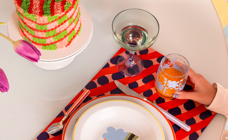 cardápio para receber amigos a noite, com mesa posta colorida com bolo, petiscos, vinho e água.
