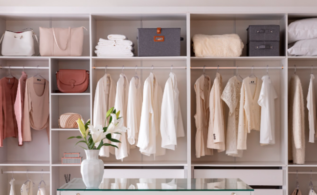 dicas para deixar o quarto organizado com um closet aberto com peças organizadas por cores, além de diversas caixas organizadoras