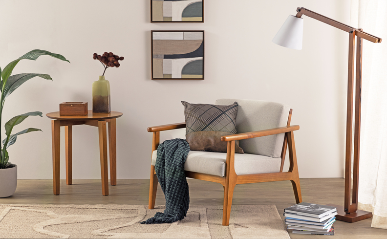 poltrona confortável para o cantinho da leitura, além de tapete, manta, luminária de chão, mesa de apoio e itens decorativos como quadros e vasos com flores e plantas.