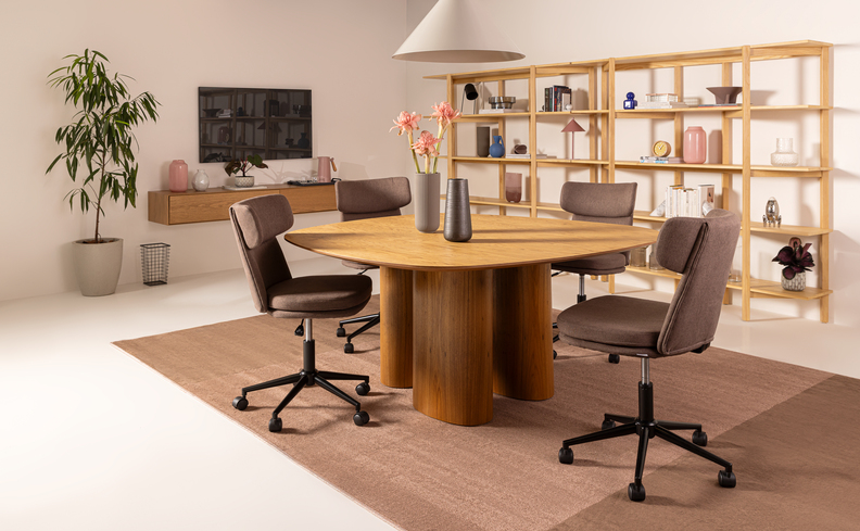 ambiente corporativo com mesa, sofá para escritório, cadeira de escritório, estante, tapete, vaso com plantas, lustre pendente e itens de organização.