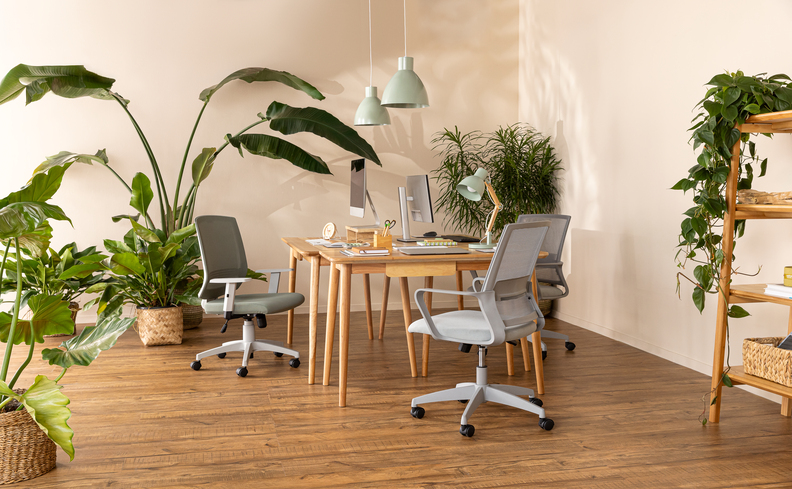 ideias decoração home office com escrivaninha de madeira, cadeira de escritório cinza, estante vazada de madeira e diversos vasos com plantas para levar vida para o ambiente.