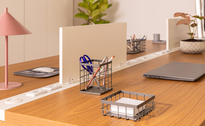 ideias para escritório home office com decoração harmoniosa e personalizada, com duas escrivaninhas de madeira, itens de organização, notebook, uma divisória no meio da mesa, itens decorativos e luminária de mesa para o escritório compartilhado.