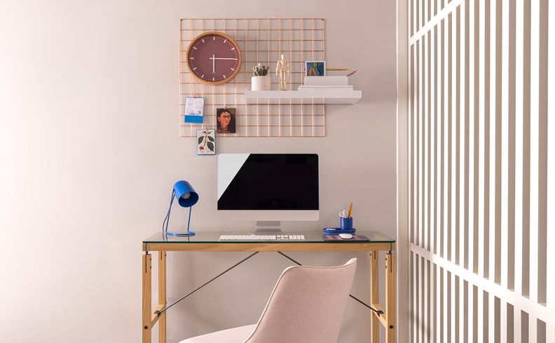 biombo divisor de ambiente em um escritório compartilhado em casa, com escrivaninha, monitor, estante, luminária de mesa e diversos itens decorativos de escritório.
