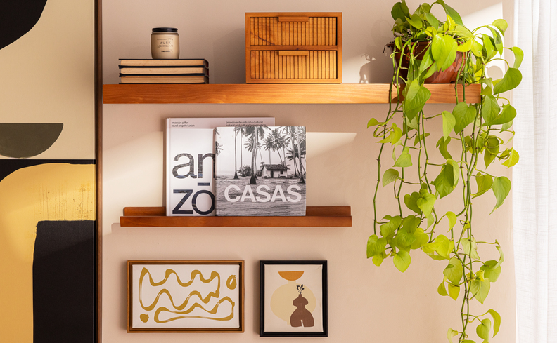 decoração boho parede na sala de estar com prateleiras, quadros, vasos com planta e tons terrosos.