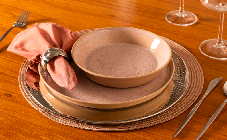 decoração dia dos namorados para fazer uma noite de fondue em casa com mesa posta completa com pratos rasos e fundos, sousplat, guardanapo de tecido, argola para guardanapo, talheres e taças, os itens em tons de rosa para complementar a decoração para essa data.