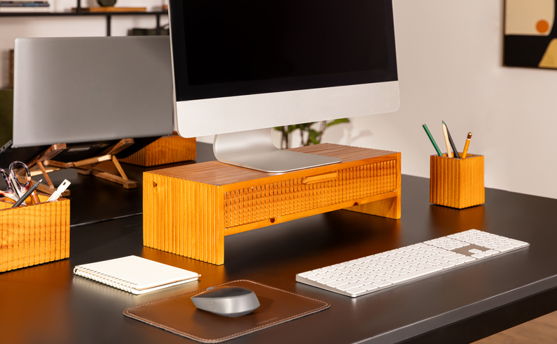 home office na sala pequena com escrivaninha, suporte de monitor, porta-lápis, mouse pad em um escritório pequeno.