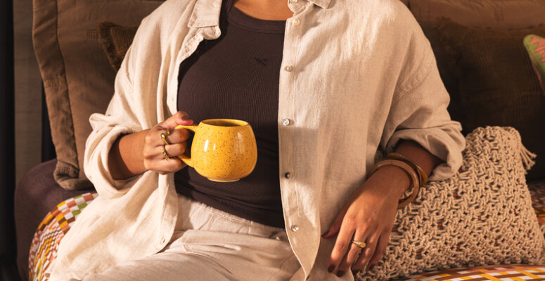 modelos de caneca para ter em casa e presentear, mulher sentada na cama segurando uma caneca amarela média..