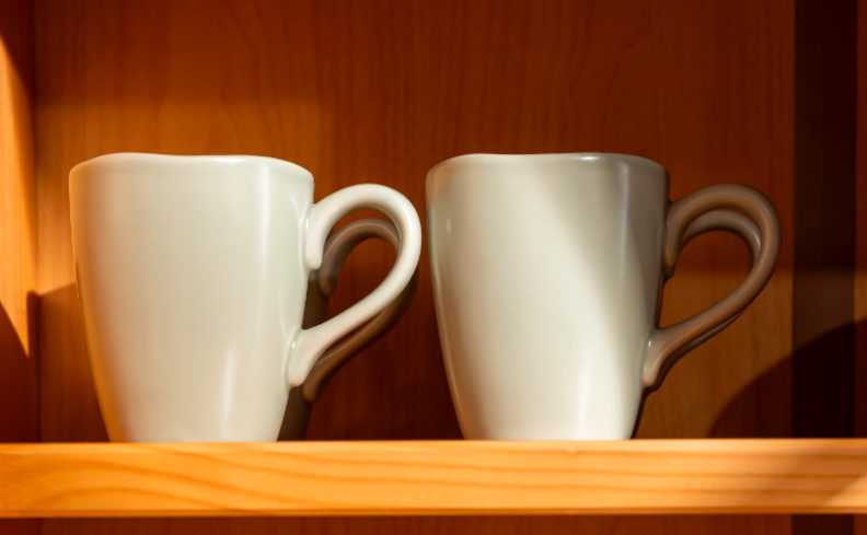 tipos de caneca com modelos em cerâmica e porcelana em prateleiras no armário da cozinha na cor cinza.