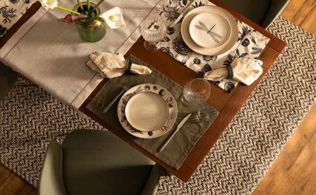 mesa posta para café da tarde com louças para mesa posta com pratos, jogo americano, talheres, vaso com flores, guardanapo de tecido e argola para guardanapo.