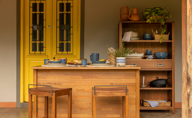 cozinhas americanas com sala, ilha de cozinha em madeira, banquetas, estante de madeira e uma porta amarela.